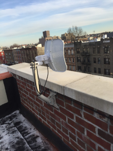 Figure 7: Ubiquiti LiteBeam AC mounted to a brick wall on a building roof.